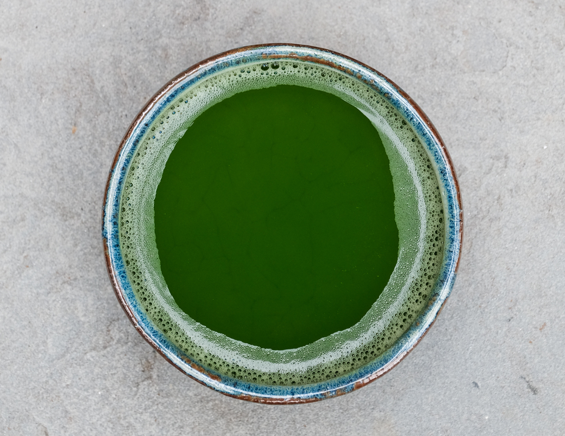 Overhead view of a bowl with freshly whisked, frothy green matcha tea