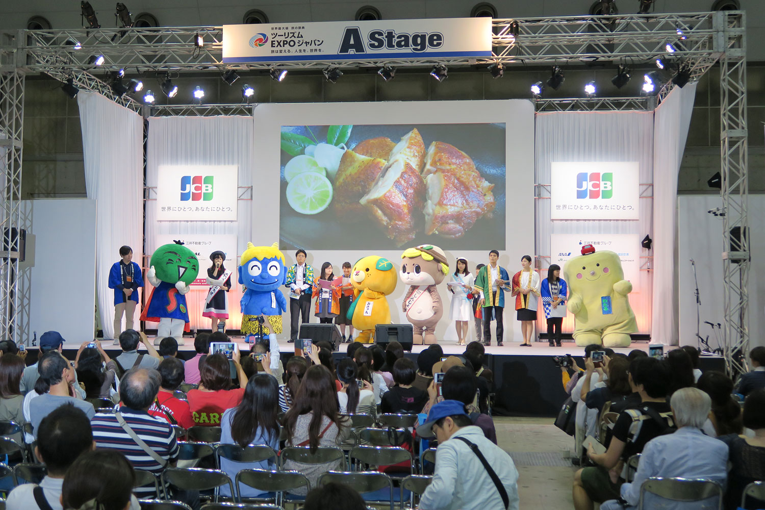 Bühne mit Maskottchen und Publikum bei der Tourism Expo Japan