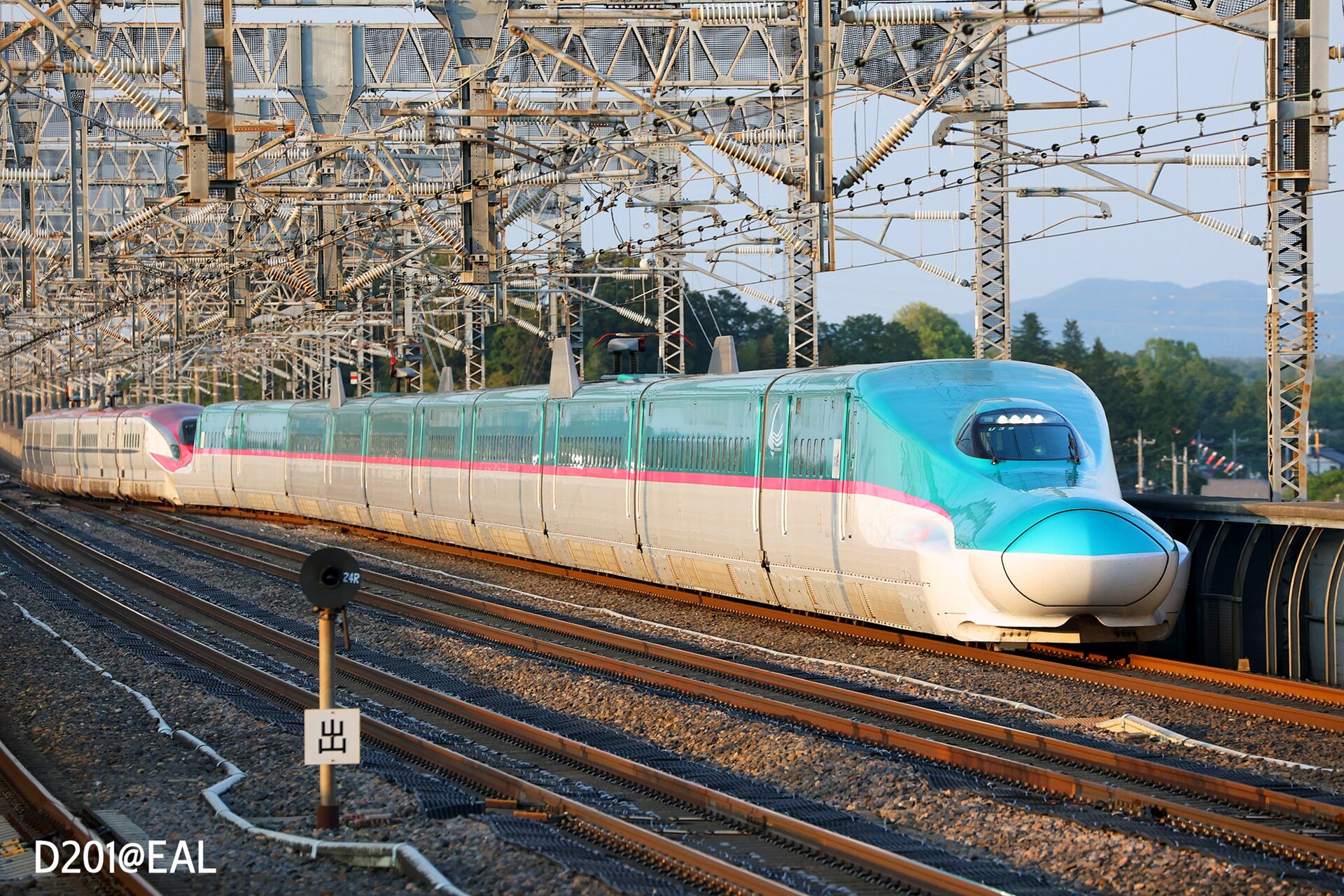 JR East E5 series Shinkansen train running on open track, front view with overhead wires