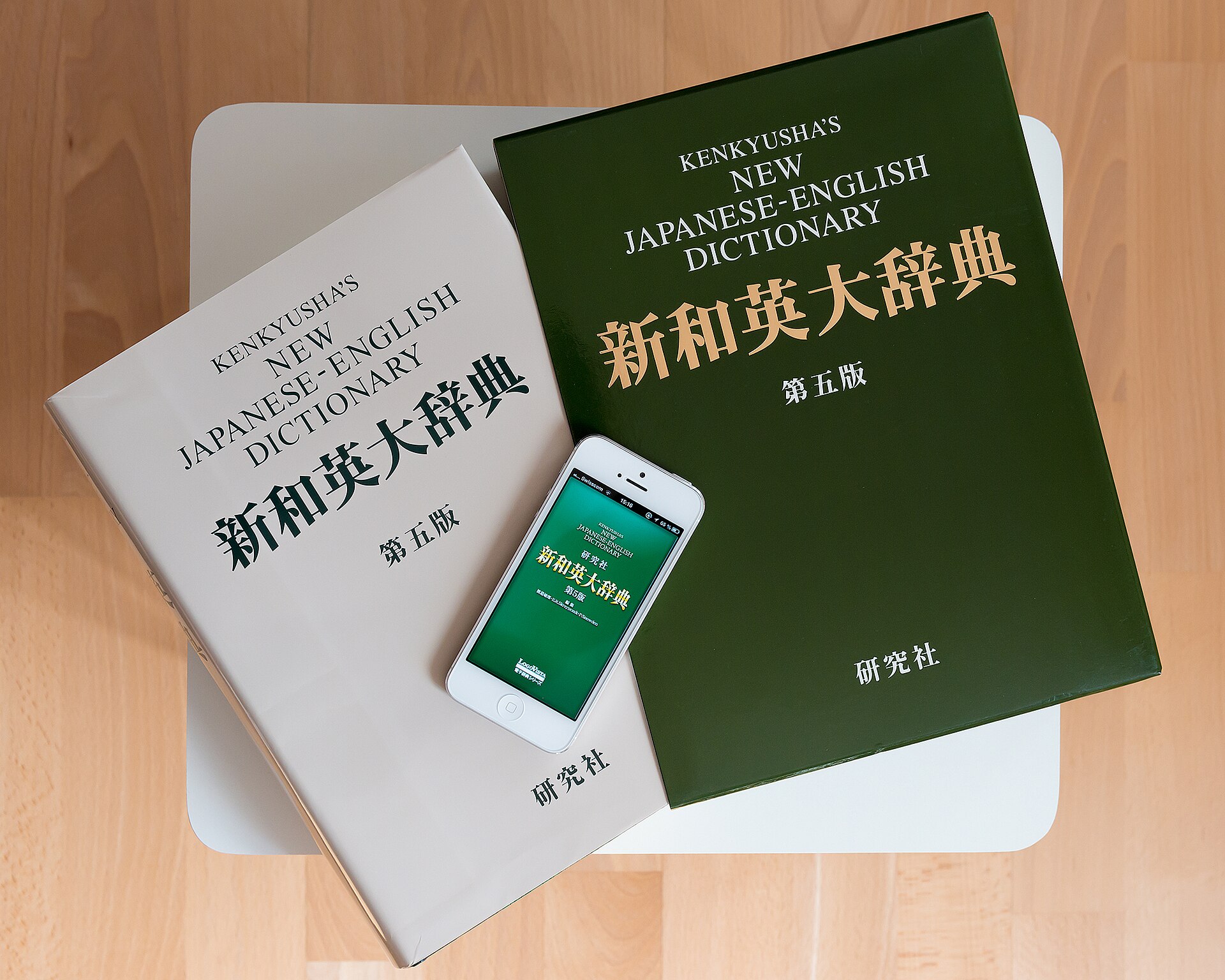Japanisch-Englische Kenkyusha-Wörterbücher neben Smartphone mit Wörterbuch-App