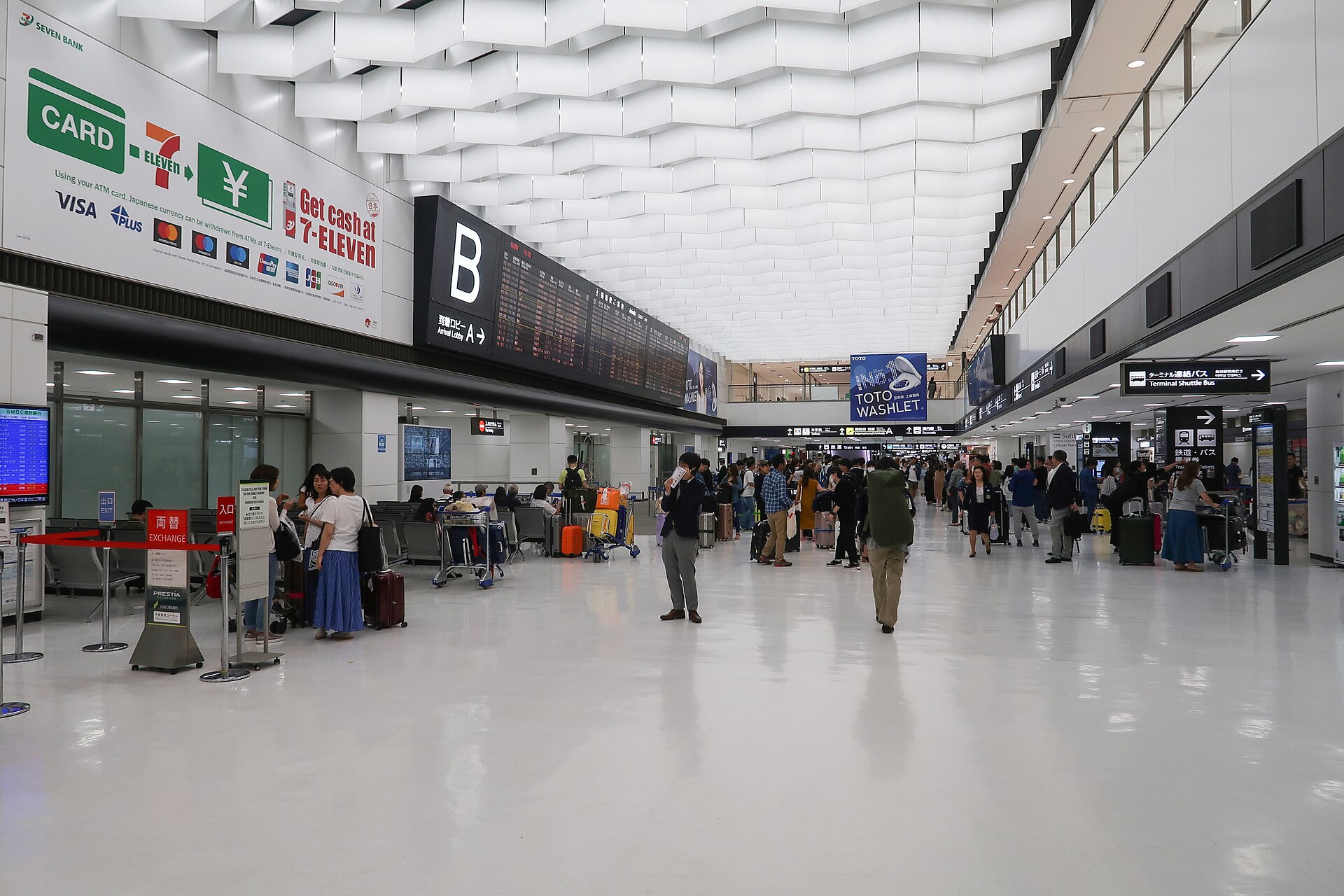 Ankunftshalle von Narita Terminal 2 mit Reisenden und Gepäckwagen