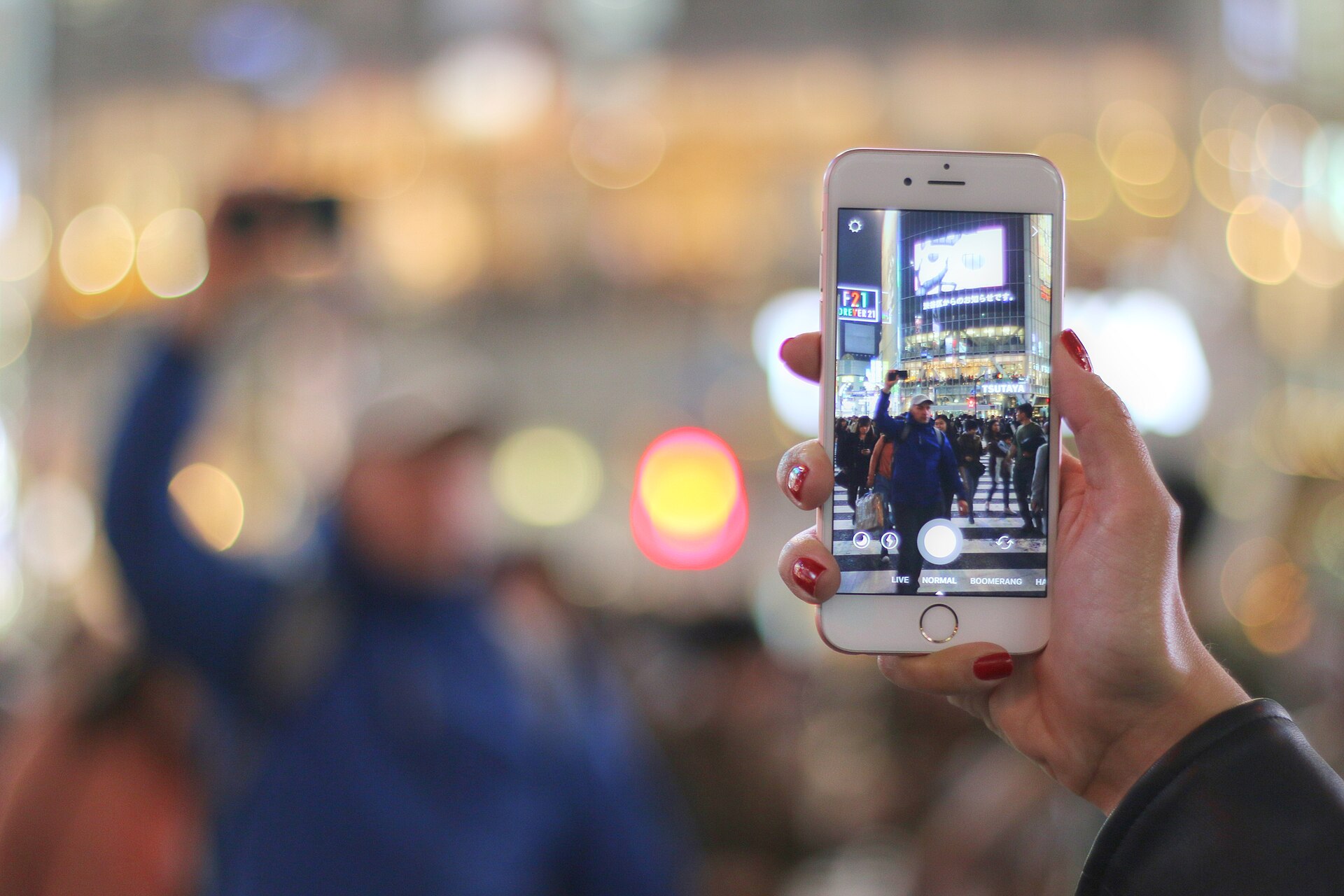 A traveler photographs Tokyo's Shibuya Crossing with a smartphone.