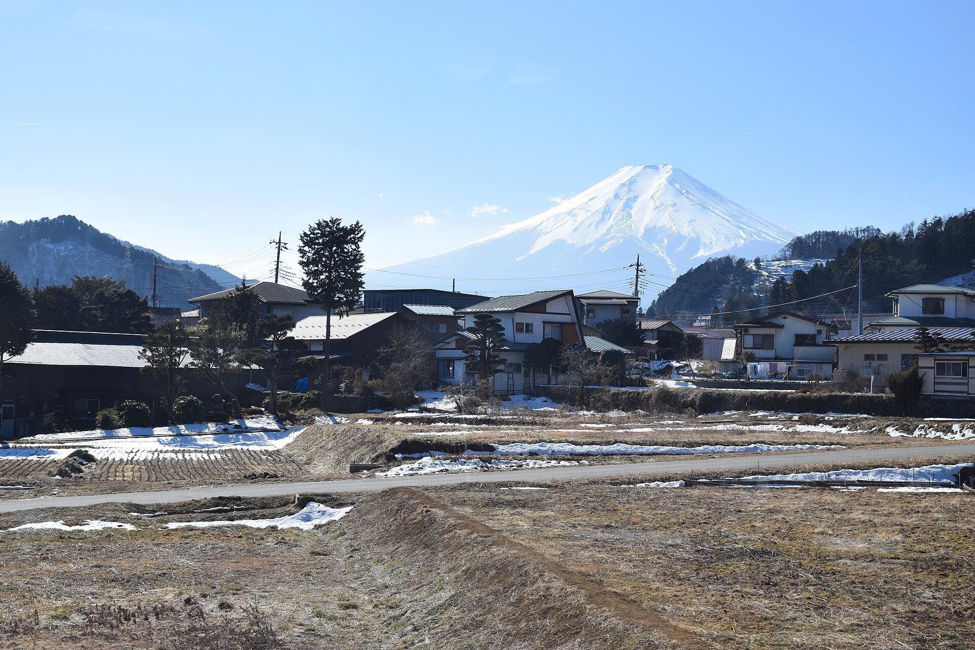 Blick auf den schneebedeckten Mount Fuji über den Dächern von Fujikawaguchiko