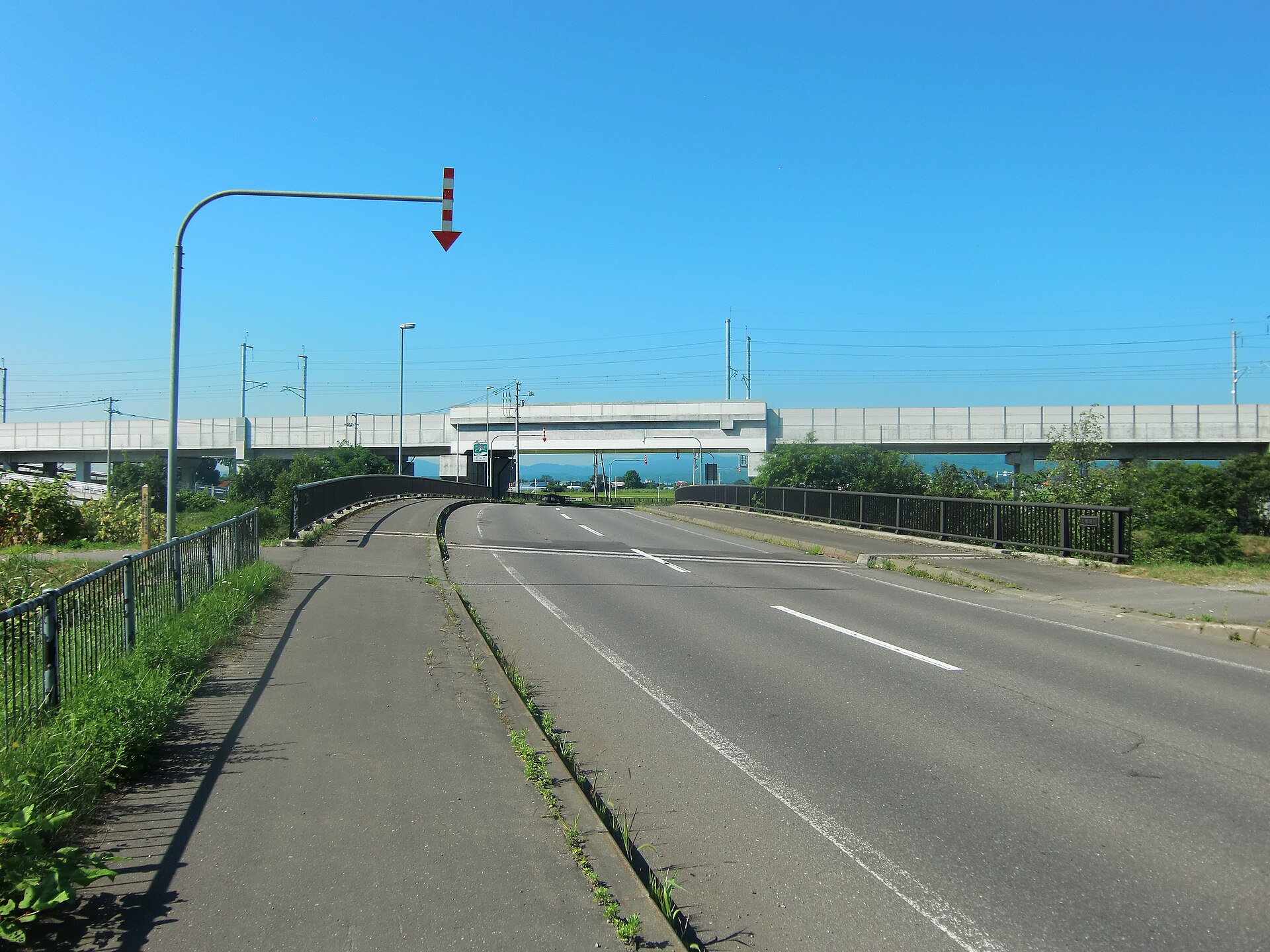 Hochbahntrasse des Hokkaido-Shinkansen kreuzt eine Straße bei blauem Himmel
